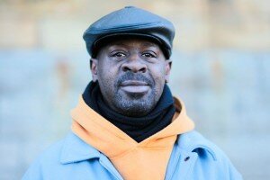 a close-up of Frank Beard, wearing a yellow hoodie under a light blue jacket