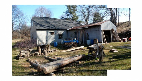 an L-shaped, warehouse-like building with logs out front