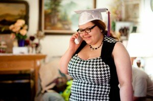 A young woman in a graduation cap and black-and-white dress on the phone