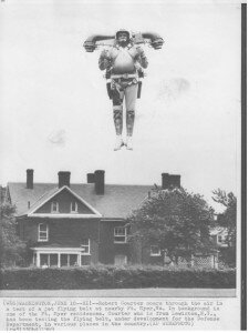 A man flying an individual lift device, with a house in the background