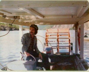 lanky young man with shaggy, longish brown hair sitting on a riverboat